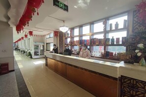 Zona de recepción de un hotel con mostrador, ventana con vistas y señalización de salida.