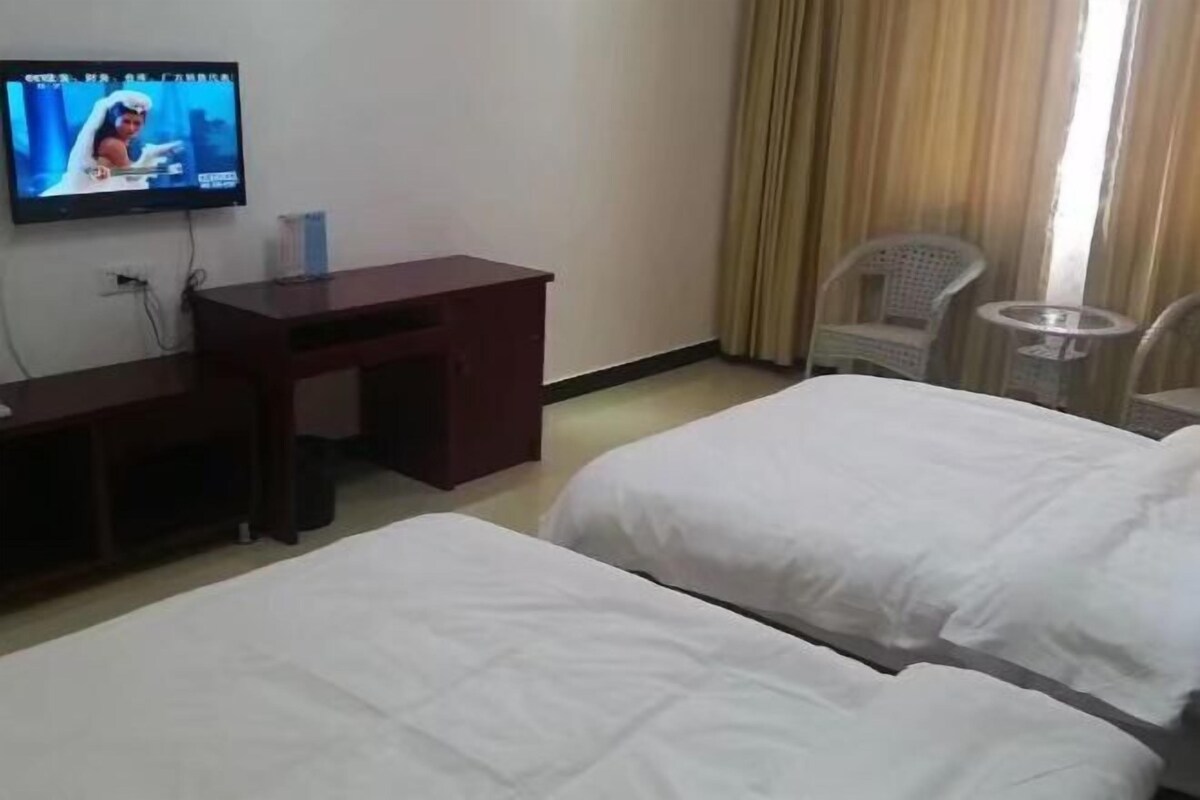 Une chambre d’hôtel avec deux lits, un bureau, une télévision et une petite table.