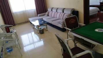 Un salon comprenant un canapé, une table basse, une table de billard et un coin repas avec des chaises.