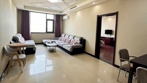 Una sala de estar moderna con sofá, sillas, una mesa de centro y televisión.