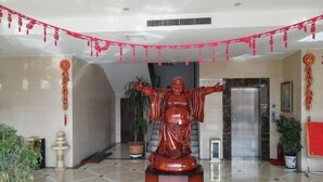 Una estatua en un vestíbulo con piso de baldosas y plantas en macetas.