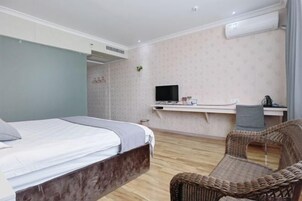 Un dormitorio con una cama, un escritorio con computadora, una silla y un equipo de aire acondicionado.