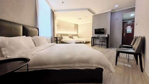 A modern hotel room with a large bed, a desk, a chair, and a television. - Jingjiang Hotel (Linhai)