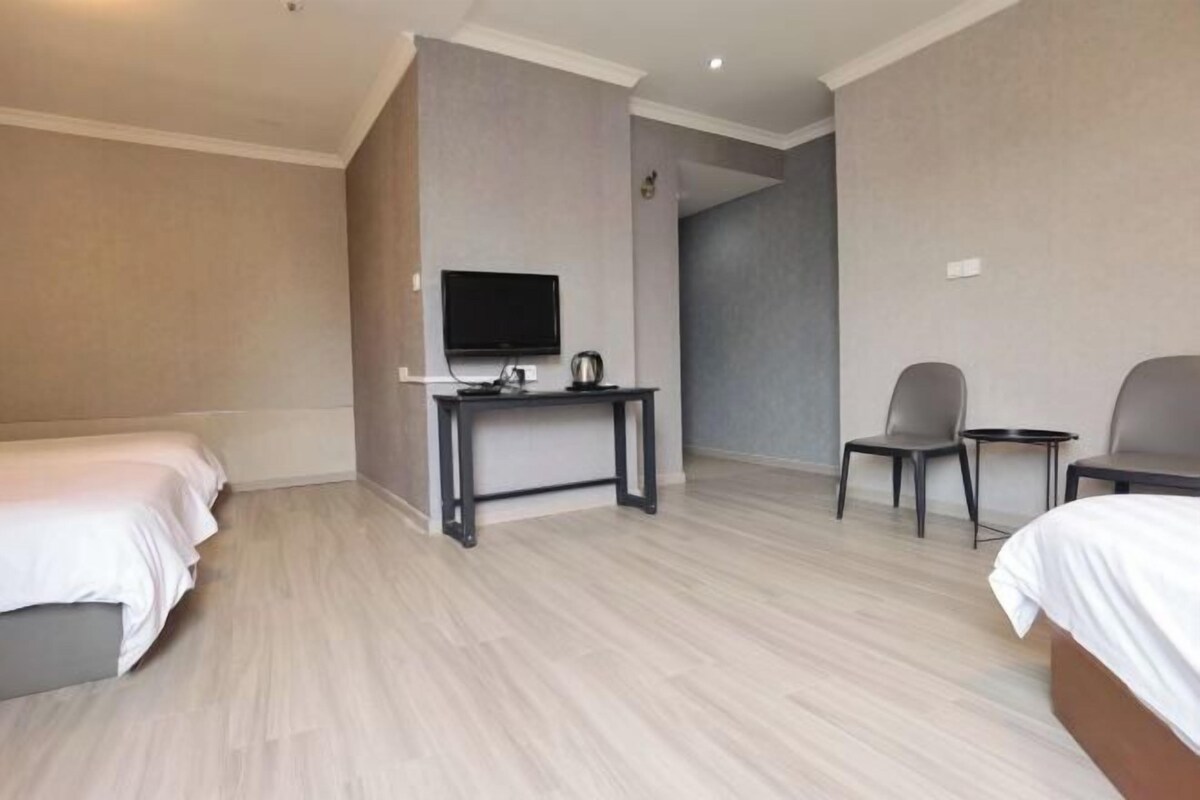 A hotel room with two beds, a desk with a television, and two chairs.