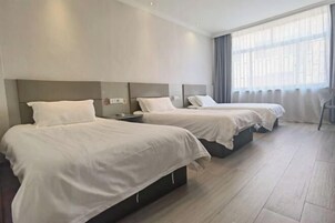 Habitación de hotel con dos camas, una mesita de noche y un amplio ventanal con cortinas.