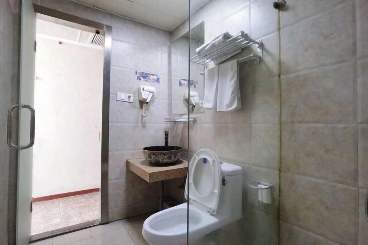 A bathroom with a toilet, a sink with a decorative bowl, and a glass shower enclosure.