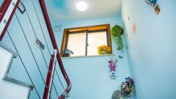 A staircase with a red handrail, a window with a wooden frame, and a wall decorated with flowers and wall art.