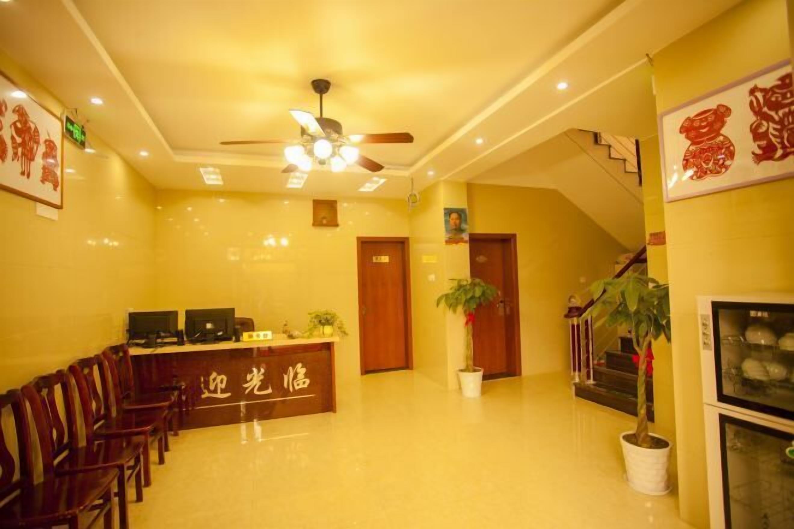 A reception area with a reception desk, chairs, a ceiling fan, and a staircase.