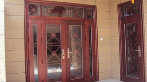 A set of wooden double doors with glass panels and a geometric pattern, set against a tiled wall. - Caiyuan Bihai Yuntian Hotel (Shengsi)