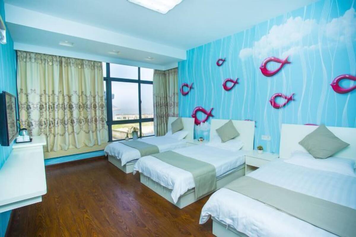 A hotel room with two beds, a large window, and a view of the city.