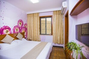 A hotel room with a bed, curtains, a window, an air conditioning unit, and a potted plant. - Caiyuan Bihai Yuntian Hotel (Shengsi)