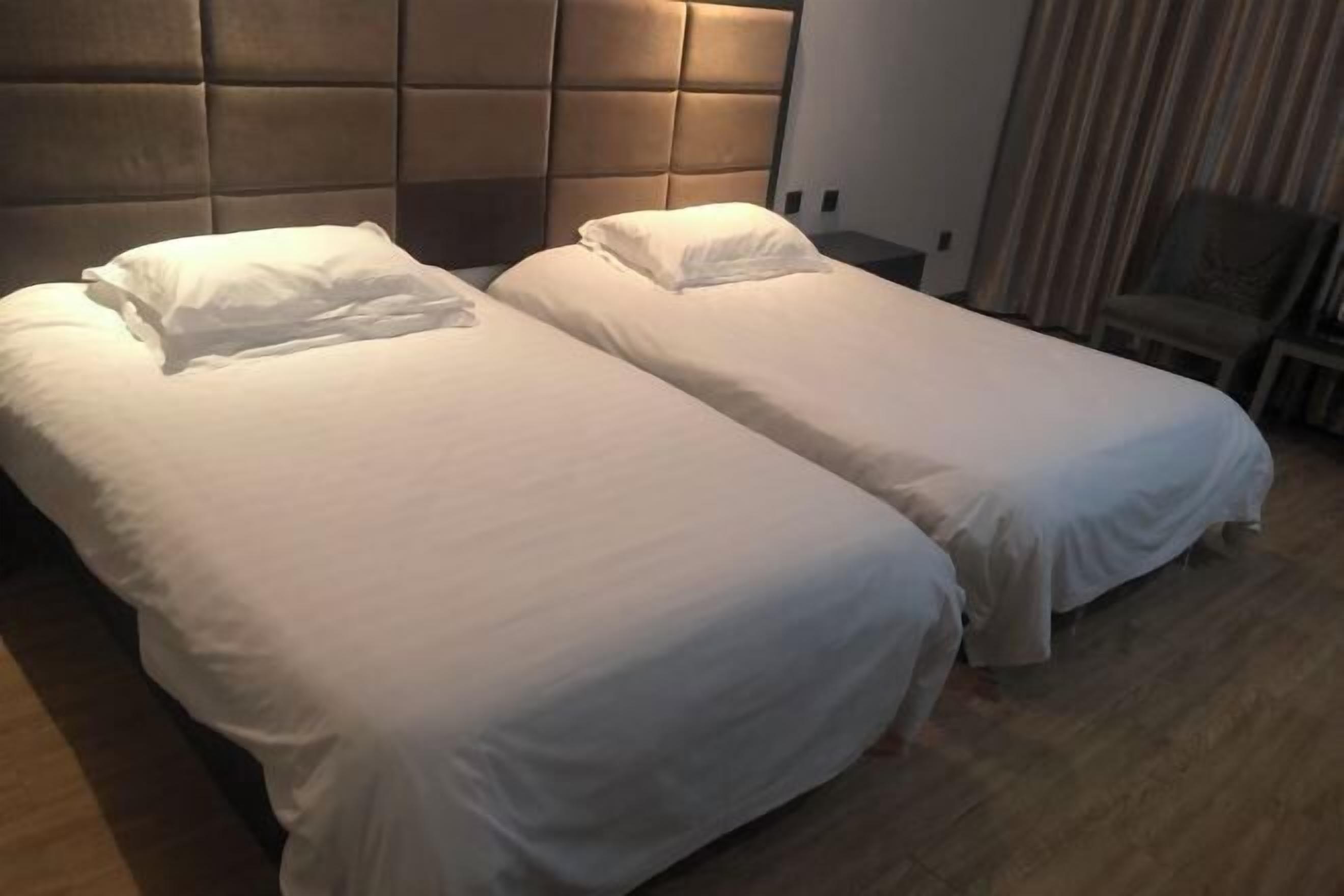 Two single beds with white linens in a hotel room.