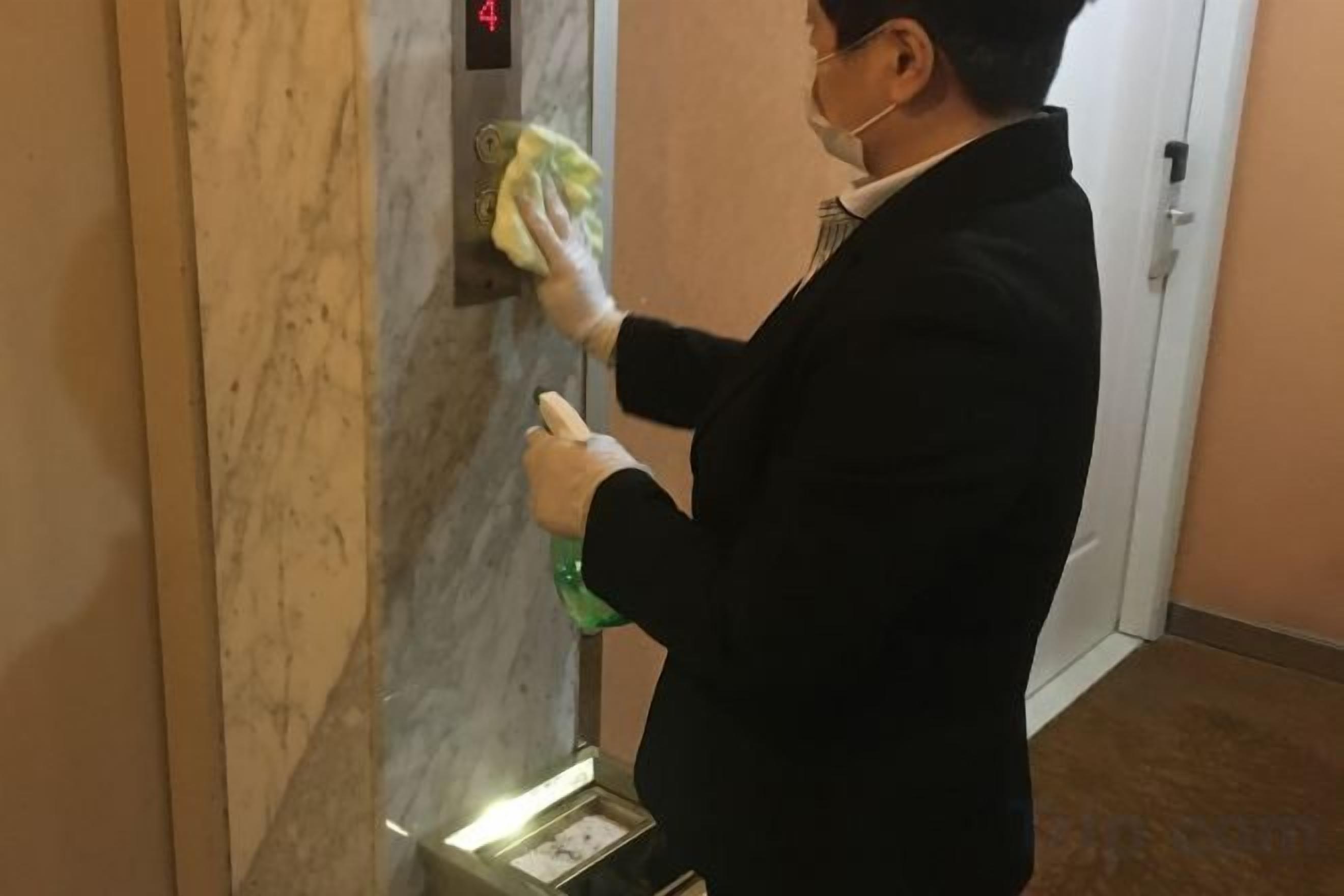 A person cleaning a marble wall in a hallway.