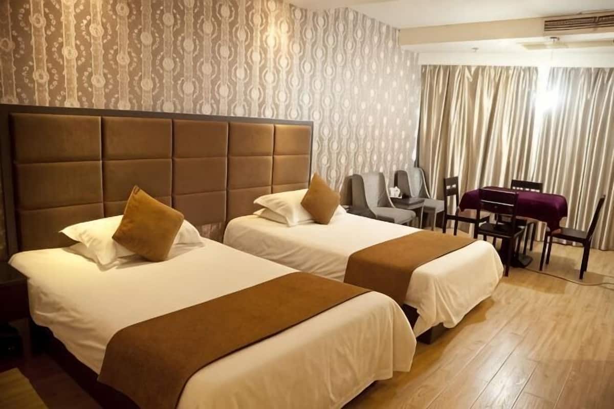 A hotel room with two beds, a desk, and a chair.