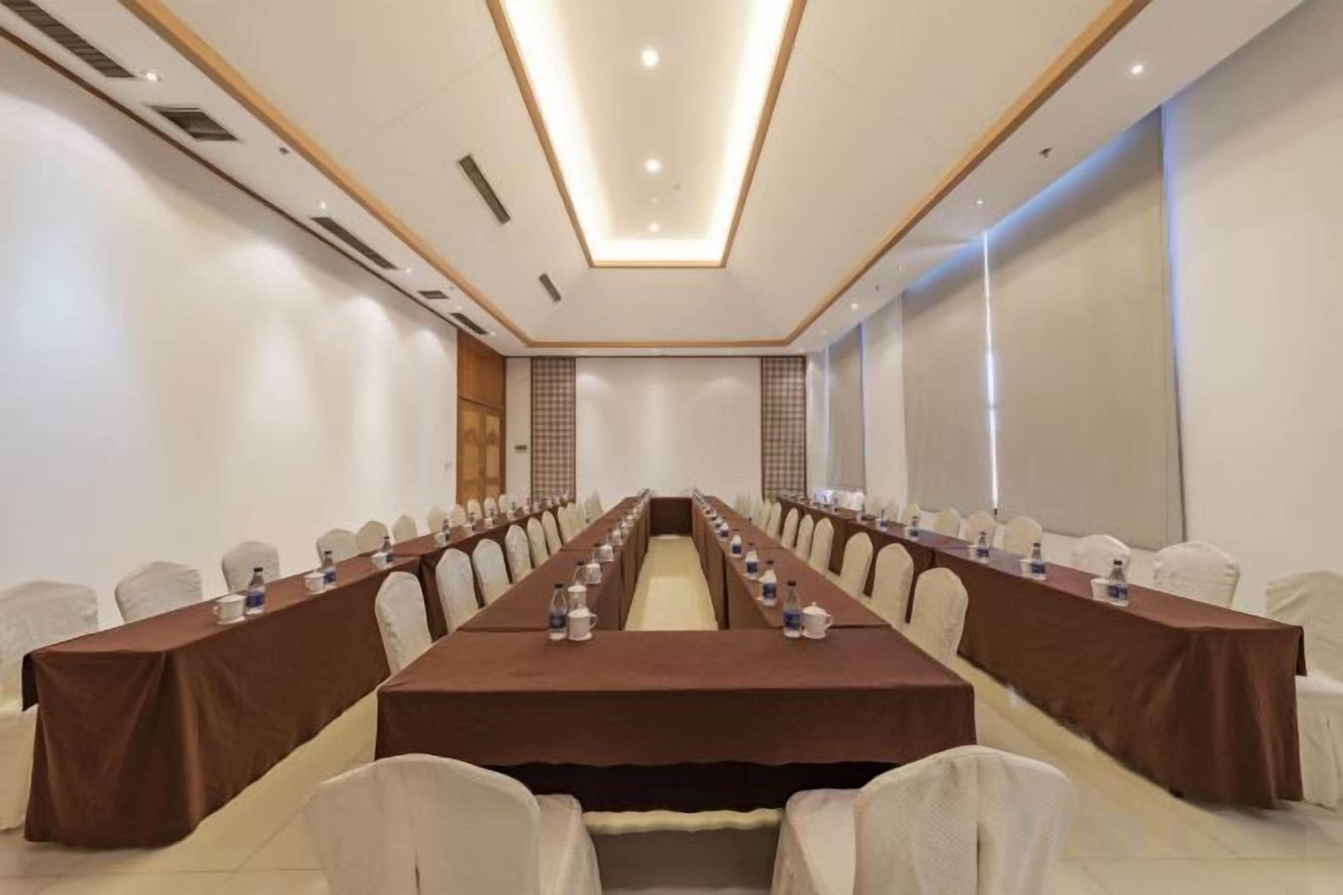 Una sala de conferències amb una taula llarga, cadires i una pantalla projectora.