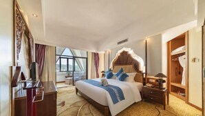 Una habitación de hotel con una cama grande, un escritorio, un armario y vistas al exterior.