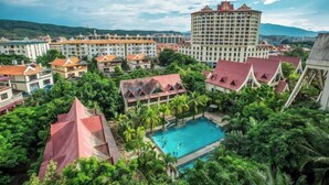 Un resort con piscina rodeado de exuberante vegetación y arquitectura tradicional.