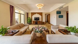 Un amplio salón con un conjunto de sofás, una mesa de centro con flores y un televisor al fondo.