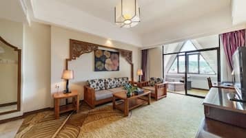 A hotel room with a sofa set, a coffee table, a TV, and a large window with a view.