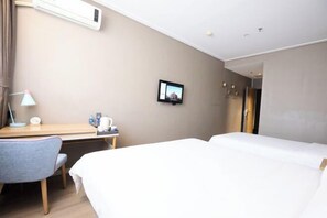 A hotel room with a bed, a desk, a chair, a TV, and a picture on the wall.
