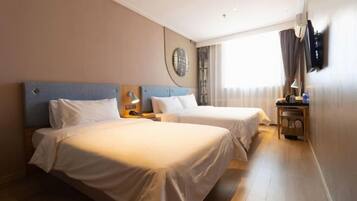 A hotel room with two beds, a round wall decoration, a TV mounted on the wall, and a window with curtains.