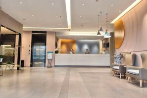 A modern hotel lobby with a reception desk, seating area, and a large circular wall feature.