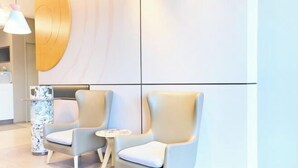 Un moderno vestíbulo de hotel con dos sillones y una pequeña mesa redonda.