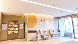 Un área de recepción moderna con una pared grande iluminada, un mostrador de recepción y un espacio para sentarse.