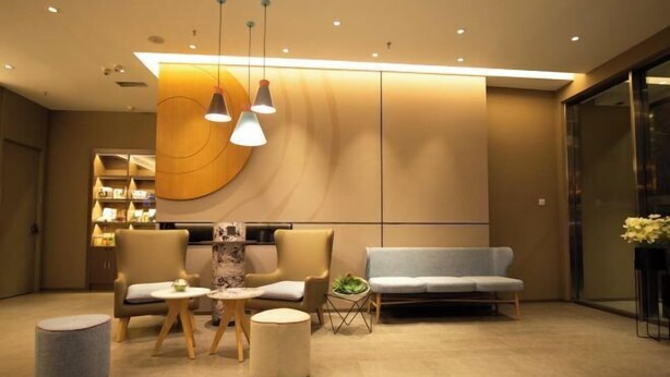 Un vestíbulo moderno con un sofá, sillas, una mesita y un muro decorativo.