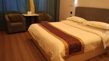 A hotel room with a bed, two armchairs, a small table, and a nightstand.