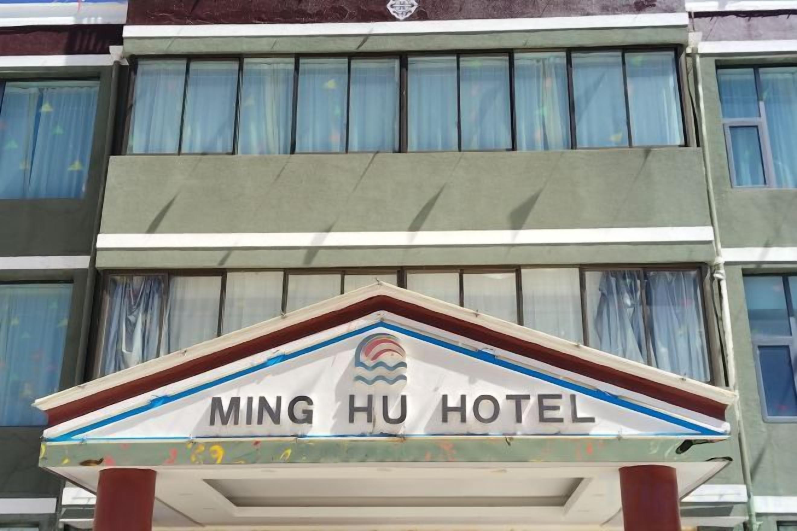 Un letrero de hotel con el nombre 'MING HU HOTEL' y un logotipo encima.