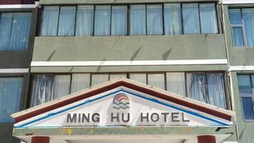 Un letrero de hotel con el nombre 'MING HU HOTEL' y un logotipo encima.