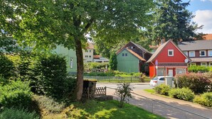 Eine Wohnstraße mit Häusern, einem Baum und einem parkenden Auto.