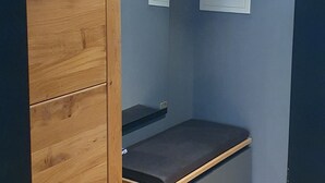 Ein Zimmer mit einem Holzschrank, einer Bank und einem kleinen Tisch.