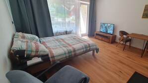 Ein Schlafzimmer mit Bett, Fernseher, Schreibtisch und Stuhl.