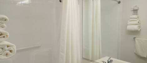 Un baño con cabina de ducha de vidrio, un lavabo blanco y un espejo.