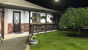 A building with a covered porch, a door labeled "OFFICE," and a well-maintained lawn with a tree and potted plants. - Upper Delaware Inn (Hancock)