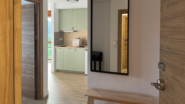 A modern kitchen with light green cabinets, a wooden countertop, and a black-framed mirror on the wall. - Apartamentos Boutique Don Miguel (Noja)