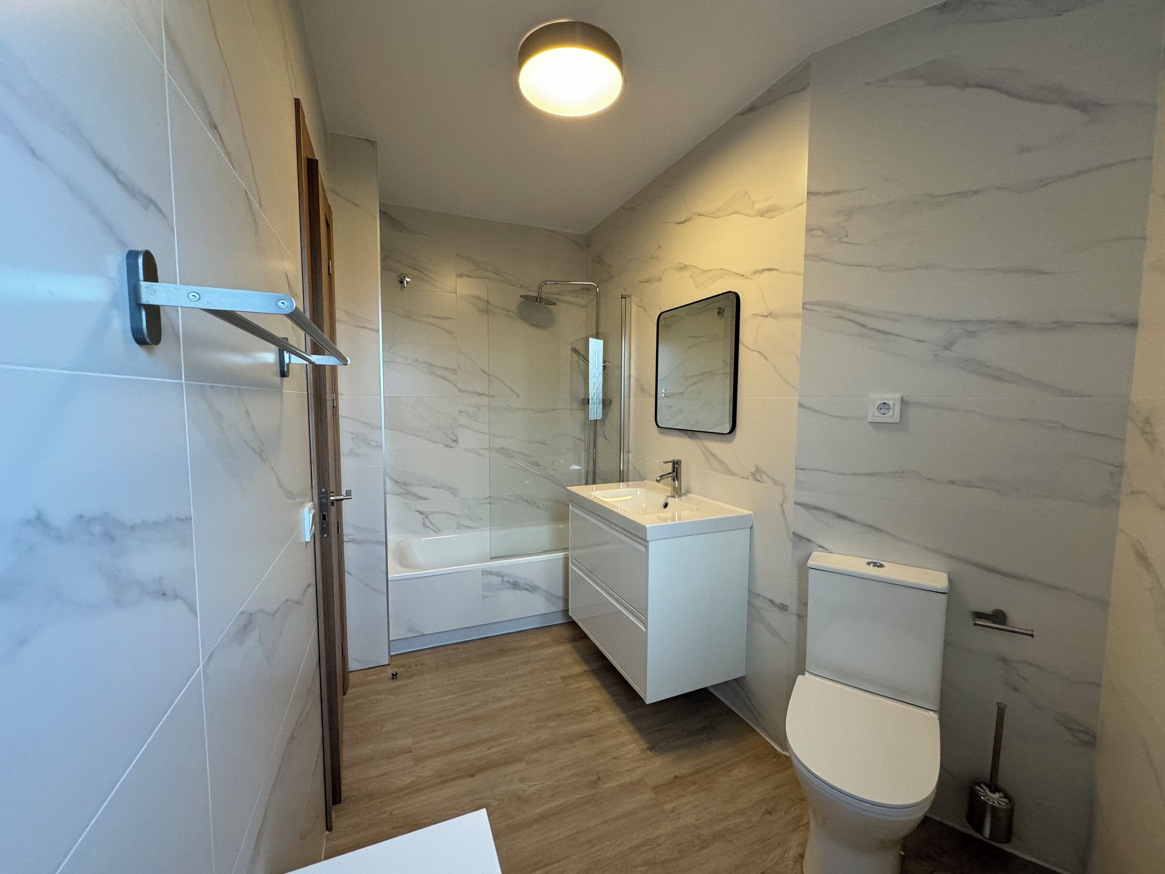Un baño moderno con cabina de ducha de vidrio, lavabo blanco y inodoro.