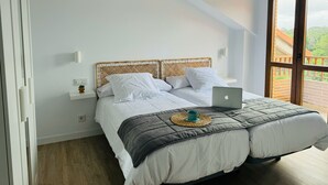 A bedroom with a bed, a laptop, and a view of a balcony. - Apartamentos Boutique Don Miguel (Noja)