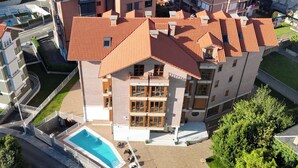 An aerial view of a multi-story building with a swimming pool, balconies, and a landscaped courtyard. - Apartamentos Boutique Don Miguel (Noja)
