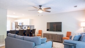 Un salon moderne doté d’un ventilateur de plafond, d’un téléviseur à écran plat et de deux canapés.