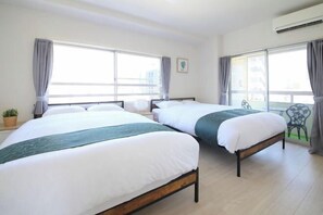 Ein Hotelzimmer mit zwei Betten, großen Fenstern, einem kleinen Tisch und einem Stuhl.