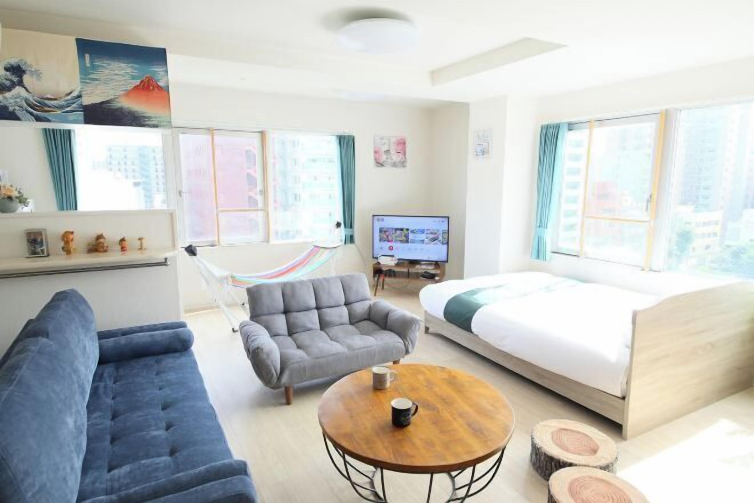 A modern hotel room with a sofa, armchair, round table, and a bed.