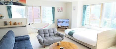 A modern hotel room with a sofa, armchair, round table, and a bed.