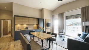 Une chambre d’hôtel moderne dotée d’un coin repas, d’un canapé et d’une grande fenêtre donnant sur la ville.