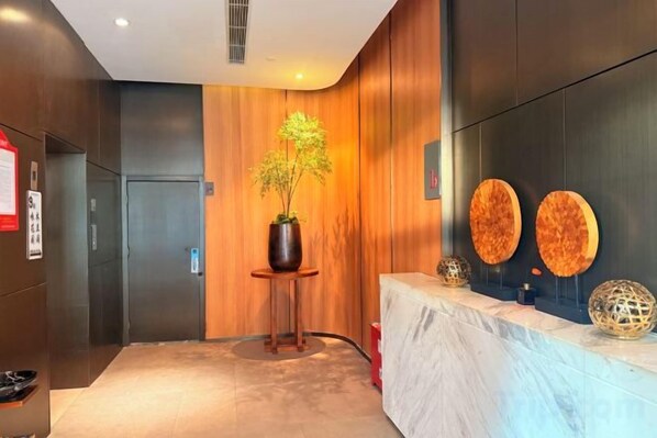 Zona de recepción con mostrador, planta en maceta y pared decorada con detalles circulares.