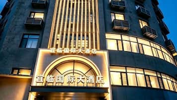 A hotel building with a prominent illuminated sign at the entrance, multiple balconies, and a modern architectural design.