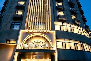 A hotel building with a prominent illuminated sign at the entrance, multiple balconies, and a modern architectural design. - Yilin International Hotel (Hefei)