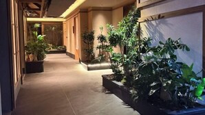 A corridor with tiled flooring, wooden beams, and potted plants. - Yilin International Hotel (Hefei)